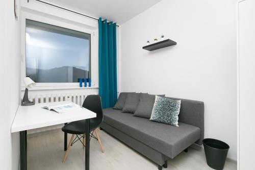 a living room with a couch and a table and a window at Rooms4Less in Gdańsk