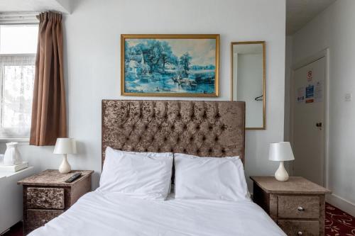 1 dormitorio con 1 cama con sábanas blancas y una pintura en Euro Hotel Harrow en Harrow