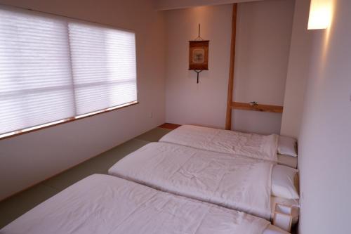 two beds in a room with a window and a clock at Guest House Ishigaki in Ishigaki Island