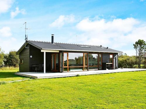 a small black house with a large grass field at 7 person holiday home in Vestervig in Vestervig