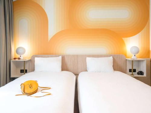 佩爾蒂伊的住宿－ibis Styles Pertuis Portes du Luberon，两张床,配有白色床单和黄色帽子