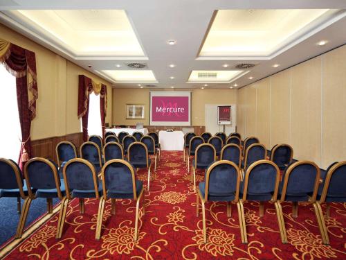 a conference room with chairs and a projection screen at voco Letchworth Hall by IHG in Letchworth