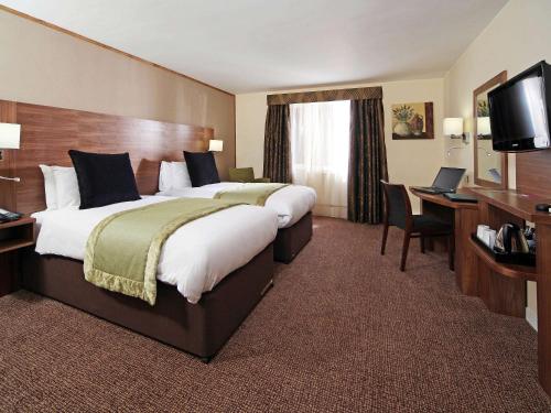 a hotel room with a large bed and a desk at voco Letchworth Hall by IHG in Letchworth
