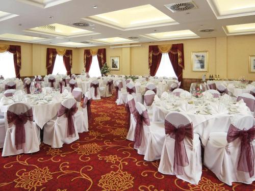 a banquet hall with white tables with bows at voco Letchworth Hall by IHG in Letchworth