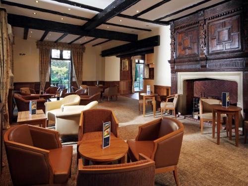 a lobby with chairs and tables and a fireplace at voco Letchworth Hall by IHG in Letchworth