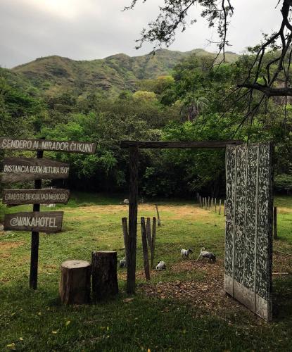 a sign in a field with mountains in the background at Waka Hotel Rural in Honda