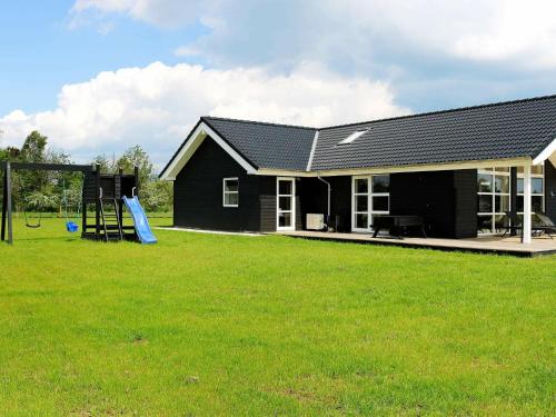 uma casa negra com um parque infantil num quintal em 8 person holiday home in Hadsund em Hadsund