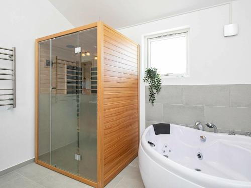a bathroom with a tub and a glass shower at 6 person holiday home in L kken in Løkken