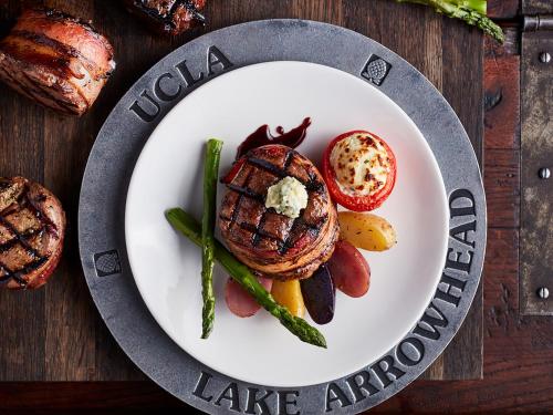 a plate with a steak and vegetables on a table at UCLA Lake Arrowhead Lodge in Lake Arrowhead
