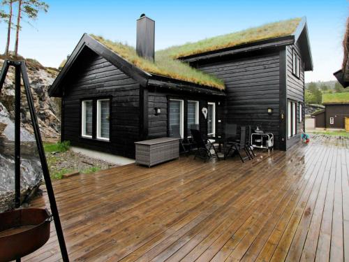 a black house with a deck with a grass roof at 10 person holiday home in SERAL in Åseral