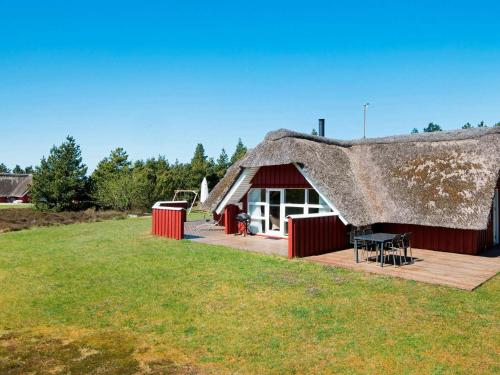 a thatch roofed house with a deck and a table at 8 person holiday home in R m in Kongsmark