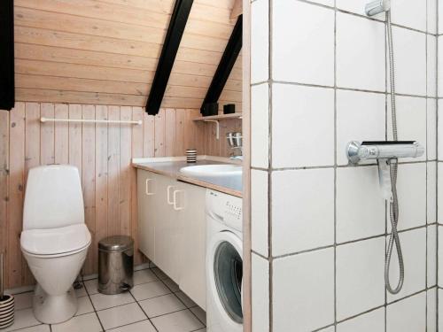 a small bathroom with a toilet and a washing machine at 8 person holiday home in R m in Kongsmark