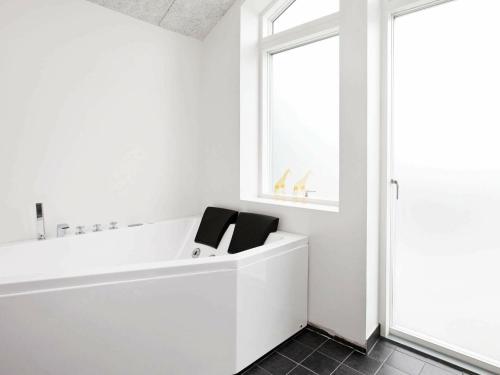 a white bathroom with a tub and a window at Three-Bedroom Holiday home in Tarm 12 in Hemmet