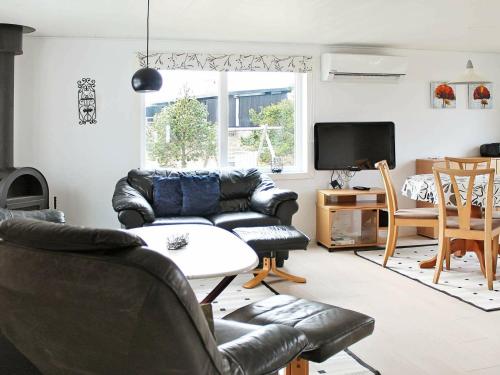 a living room with black leather furniture and a tv at 6 person holiday home in R m in Bolilmark