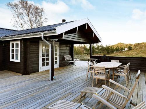 une terrasse en bois avec une table et des chaises. dans l'établissement 6 person holiday home in lb k, à Ålbæk