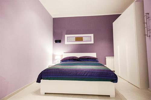 1 dormitorio con paredes moradas y 1 cama blanca en ComfortHouse Plus, en Lido di Ostia