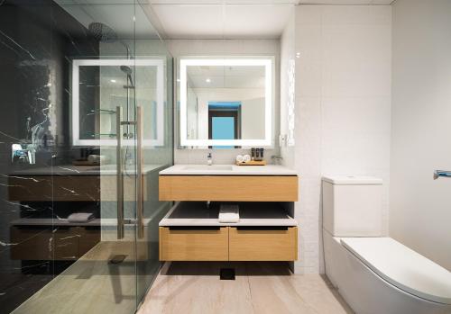 a bathroom with a sink and a glass shower at Novotel Tainui Hamilton in Hamilton
