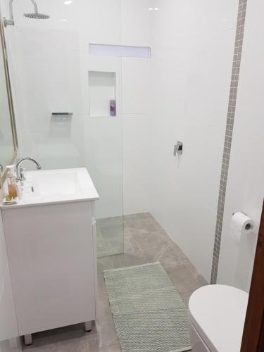 een witte badkamer met een wastafel en een douche bij Never Inn in Kiama
