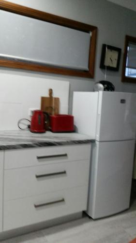 een keuken met een witte koelkast en een rood apparaat bij Never Inn in Kiama