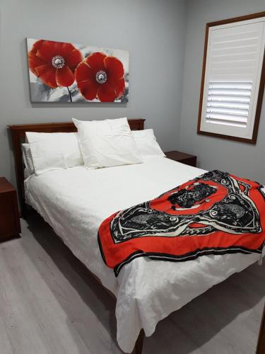 een slaapkamer met een bed met rode bloemen aan de muur bij Never Inn in Kiama