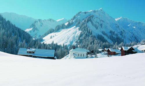 a small village in the snow with a mountain at Hotel Almhof Rupp in Riezlern