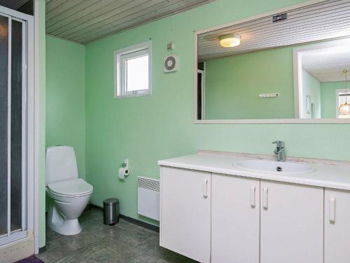 a green bathroom with a toilet and a sink at 8 person holiday home in Stege in Stege