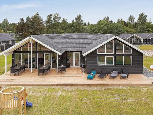 Vejbyにある16 person holiday home in Vejbyのデッキ(椅子付)と遊び場のある家