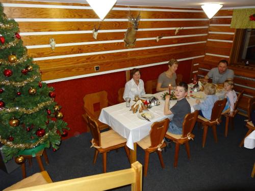a group of people sitting at a table with a christmas tree at Horská chata Hubert in Bedřichov