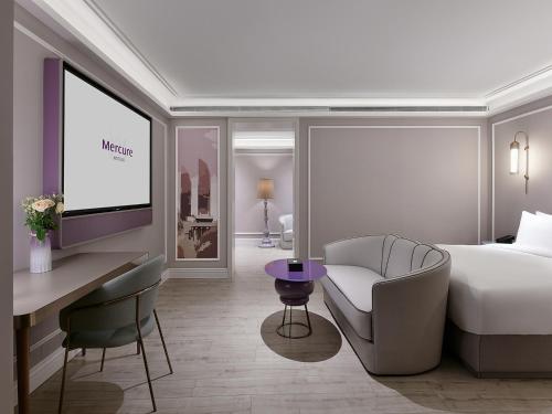 a bedroom with a bed and a desk and a tv at Mercure Xiamen Zhongshan Road Pedestrian Street Seaview in Xiamen