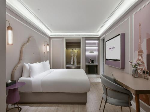 a bedroom with a large white bed and a desk at Mercure Xiamen Zhongshan Road Pedestrian Street Seaview in Xiamen