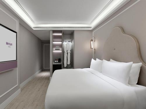 a bedroom with a large white bed and a tv at Mercure Xiamen Zhongshan Road Pedestrian Street Seaview in Xiamen