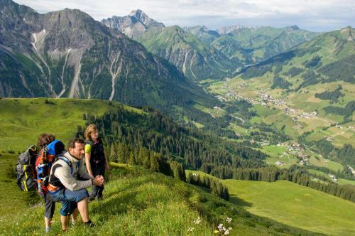 a group of people on a hill with a view of mountains at Hotel Almhof Rupp in Riezlern