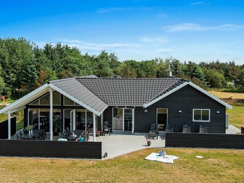 una gran casa negra con un gran patio en 18 person holiday home in Bl vand, en Blåvand