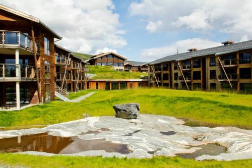 a campus with a building and a pond in the grass at Norefjell Ski & Spa in Noresund