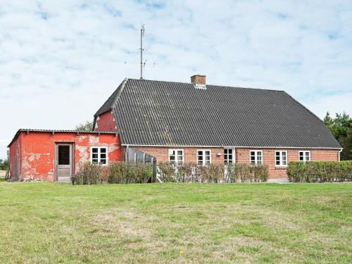 um celeiro vermelho com um telhado preto num campo em 5 person holiday home in R m em Toftum