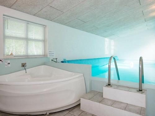 a white tub in a bathroom with a blue wall at 10 person holiday home in Ebeltoft in Ebeltoft