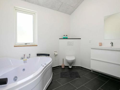 uma casa de banho branca com uma banheira e um WC em 8 person holiday home in L s em Læsø