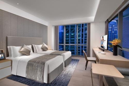 a hotel room with a bed and a desk and a window at Ascott Raffles City Chongqing in Chongqing