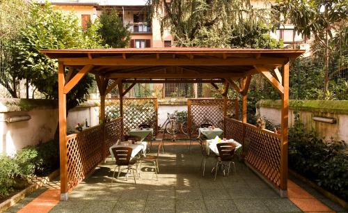 une pergola en bois avec des tables et des chaises sur une terrasse dans l'établissement Hotel Sabatino Milan, à Milan