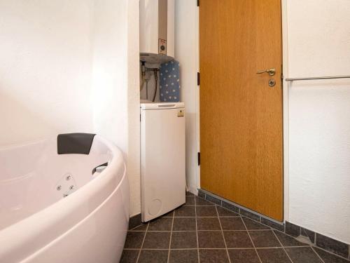 a small bathroom with a tub and a refrigerator at 6 person holiday home in Knebel-By Traum in Skødshoved Strand