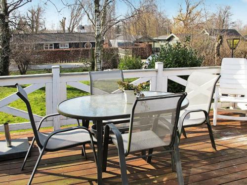 a glass table and chairs on a deck at 6 person holiday home in Str by in Strøby