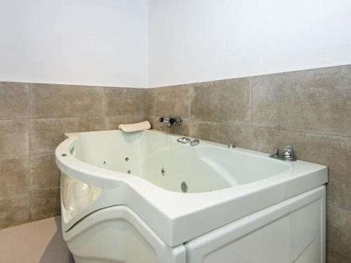 a white bath tub sitting in a bathroom at 14 person holiday home in R m in Kongsmark
