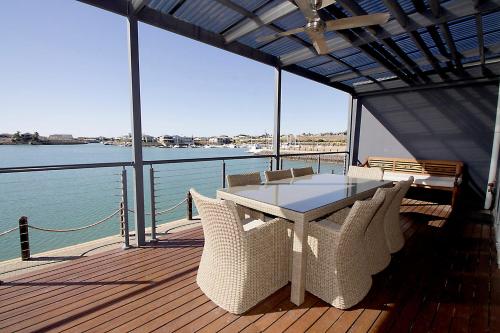 une table et des chaises sur une terrasse avec vue sur l'eau dans l'établissement Wallaroo Marina Apartments, à Wallaroo