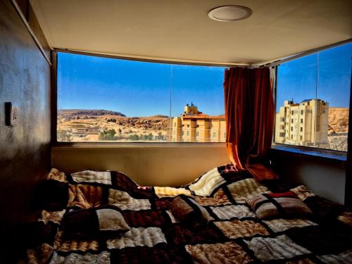 łóżko w pokoju z dużym oknem w obiekcie Petra Cabin Hostel w mieście Wadi Musa