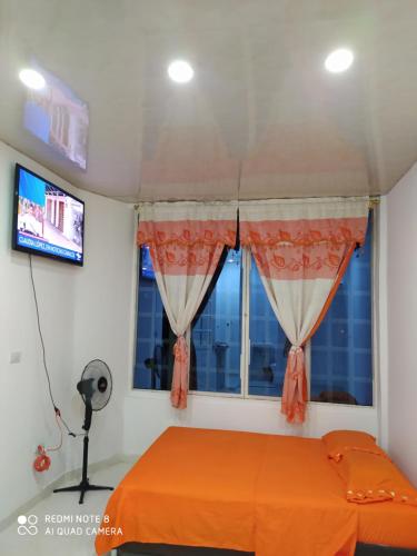 1 dormitorio con cama de color naranja y ventana en Apartaestudios El Descanso, en Cali