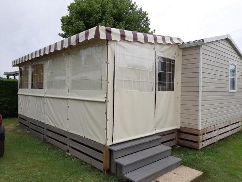 a large white shed sitting in the grass at La Palmyre - Les Mathes - Mobil home 3 ch LUXUEUX de 40m2 - Grand emplacement dans village loisirs 4 étoiles - "les Charmettes 394" proche FUN ZONE in Les Mathes