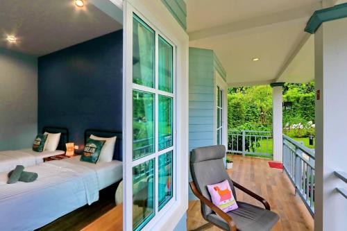 a bedroom with a balcony with two beds and a chair at Little Cottage in Chanthaburi