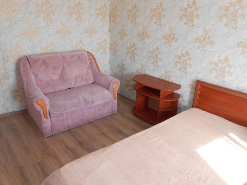 una camera con una sedia rosa e un letto di Однокомнатная квартира рядом с метро Оболонь a Kiev