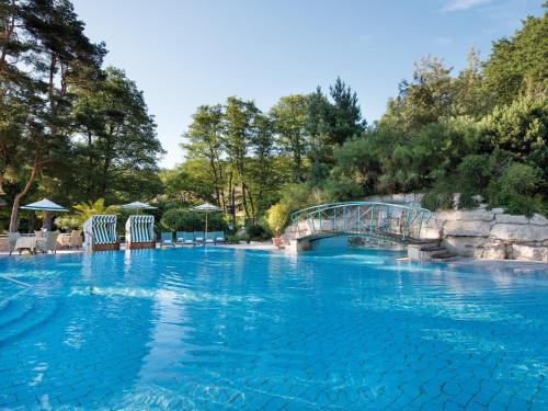 a large swimming pool with a bridge and trees at Hotel Bernstein Prerow in Prerow