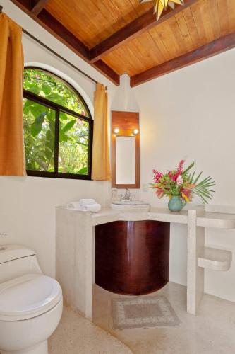 a bathroom with a toilet and a sink and a mirror at Anamaya Resort in Montezuma